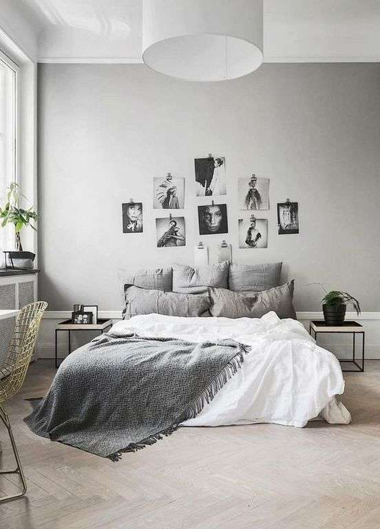 Galerie de photos noir et blanc au-dessus du lit dans une chambre grise lumineuse