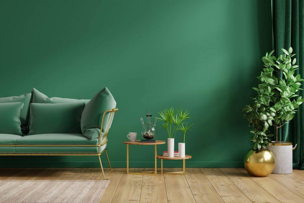 Salon vert avec mur vert foncé, sofa vert et plantes vertes.