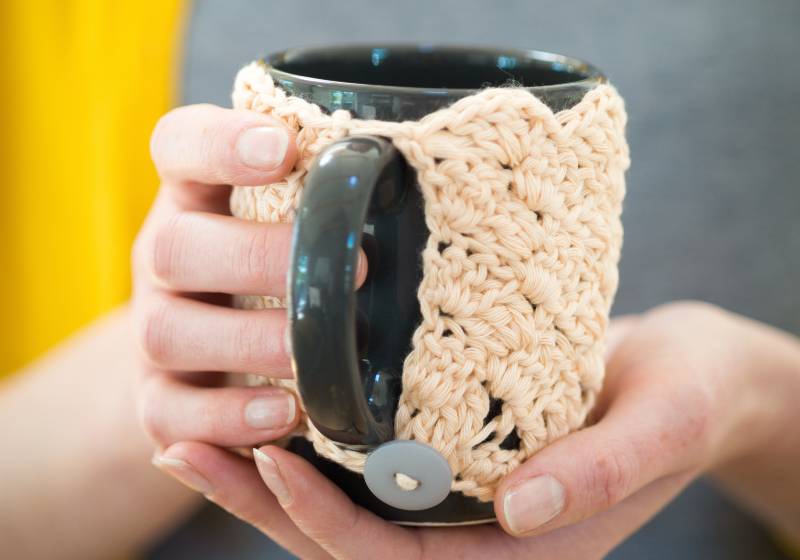 Mains tenant un mug en tricot douillet | Marion's Cozy Mug Warmer