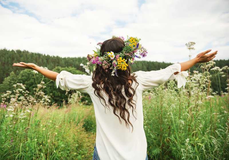 Portrait de style de vie estival d'une belle jeune femme brune aux longs cheveux bouclés dans une couronne de fleurs sauvages | Flower Crowns